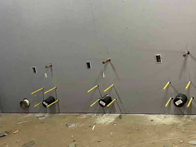 Drywall hanging on a large commercial wall with electrical boxes cut in
