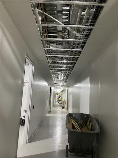 Long finished drywall corridor with suspended ceiling grid